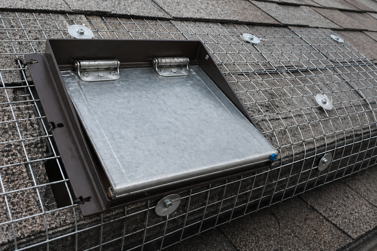 A professional one-way-door installed on a roof for humane raccoon removal.